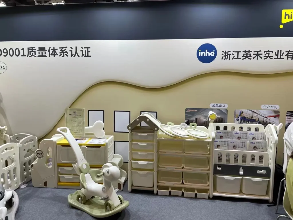 A minimalist multi-tier children's storage cabinet, house-shaped drawer units, and a cream and olive green toddler rocking horse on display at the trade show.