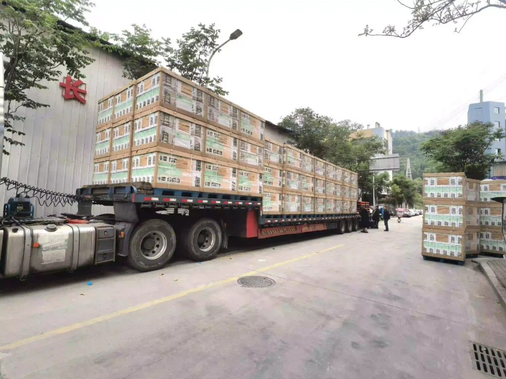 A fully loaded heavy-duty flatbed transport truck packed to legal capacity with master cartons of Inhekids furniture solutions for the Americas.
