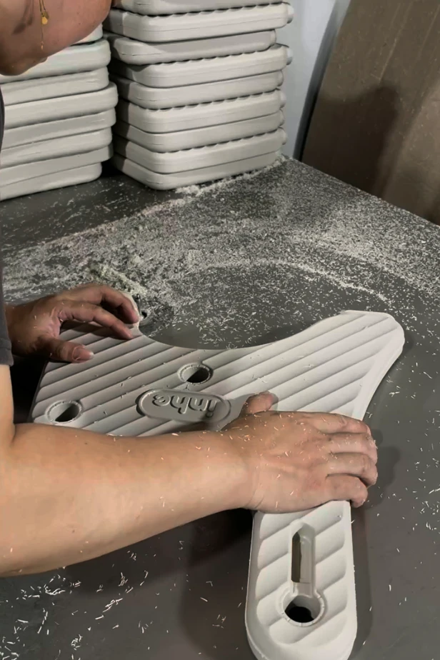 Inhekids factory worker manually trimming and deburring edges of blow molded plastic furniture panel