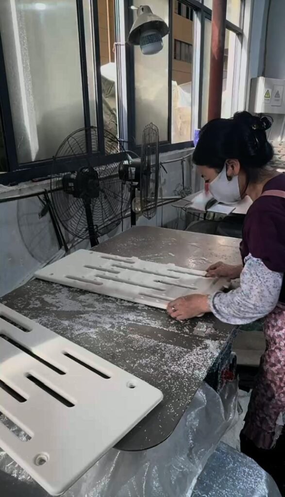 Technician deburring and smoothing interior slots of plastic components at Inhekids finishing station