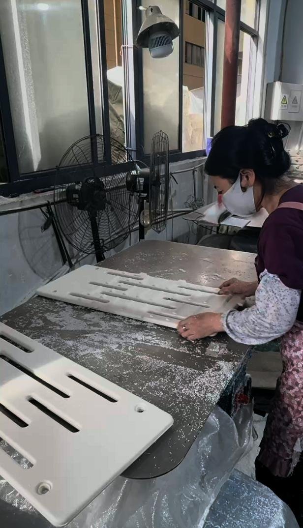Technician deburring and smoothing interior slots of plastic components at Inhekids finishing station
