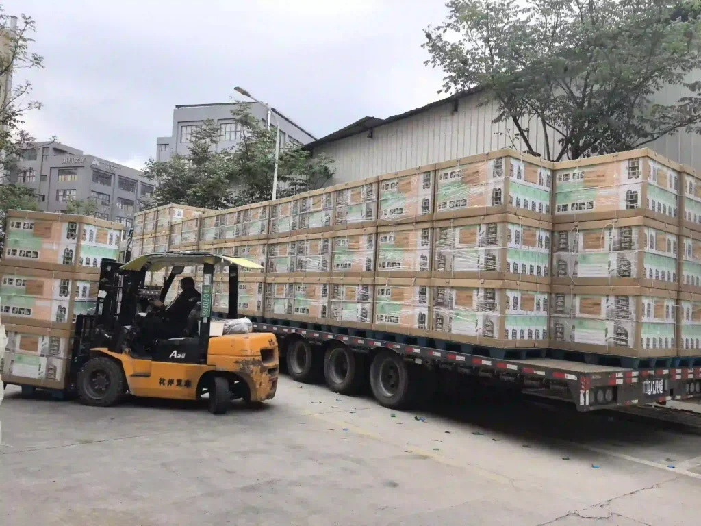 A heavy forklift operator carefully lifting stretch-wrapped industrial pallets of wholesale preschool furniture at the Inhekids manufacturing plant terminal.